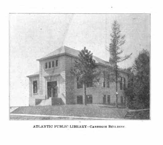 Black and white image depicting the exterior of the Atlantic Public Library. Trees are partially blocking the view of the building. 