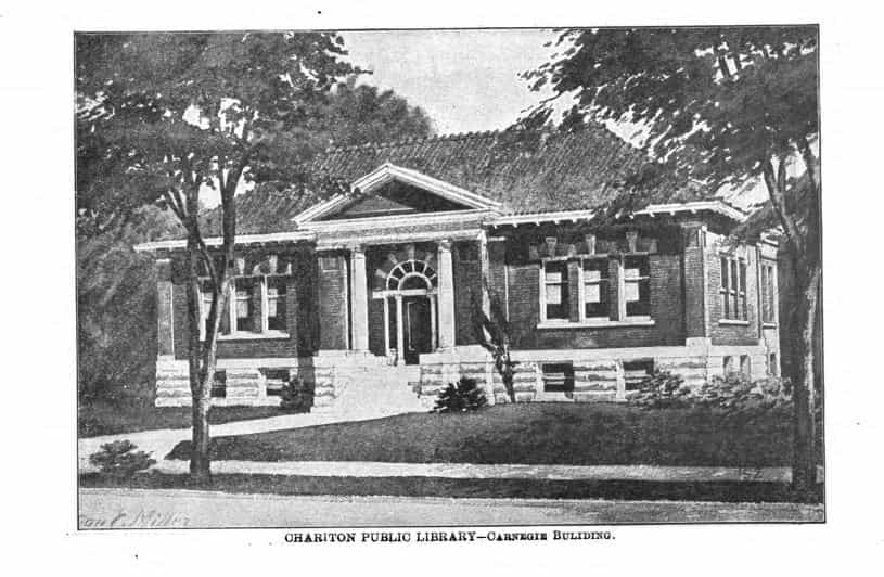 Black and white image showing the exterior of the Chariton Public Library. Trees partially blocks the view of the building. 