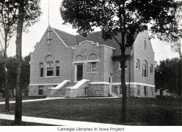 Black and white image showing the exterior of the Algona Public Library. Tree partially blocking view of the building. Taken from the 3rd Report of the Iowa Library Commission, coverage 1905-1906. (Published in 1907), opposite page 26.