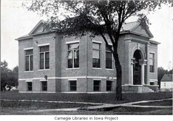 Black and white image depicting the exterior of the Indianola Public Library, with a tree blocking part of the image. 