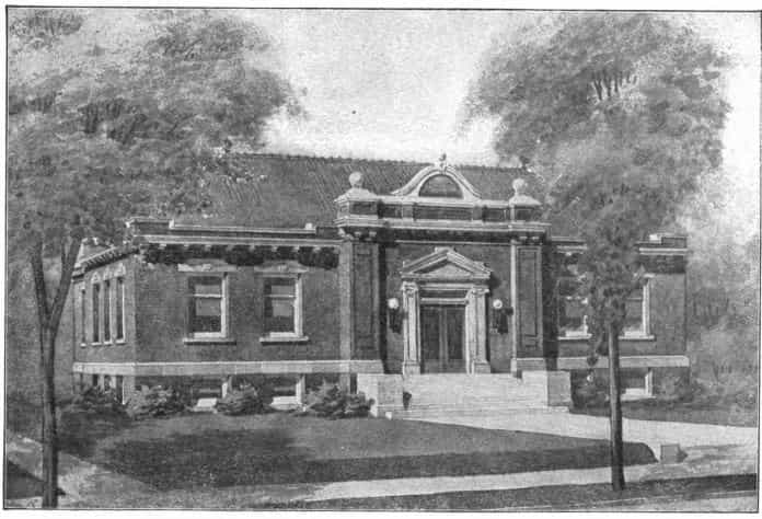 Black and white image showing the front exterior of the Shenandoah Public Library. Trees are partially blocking the view of the building. 