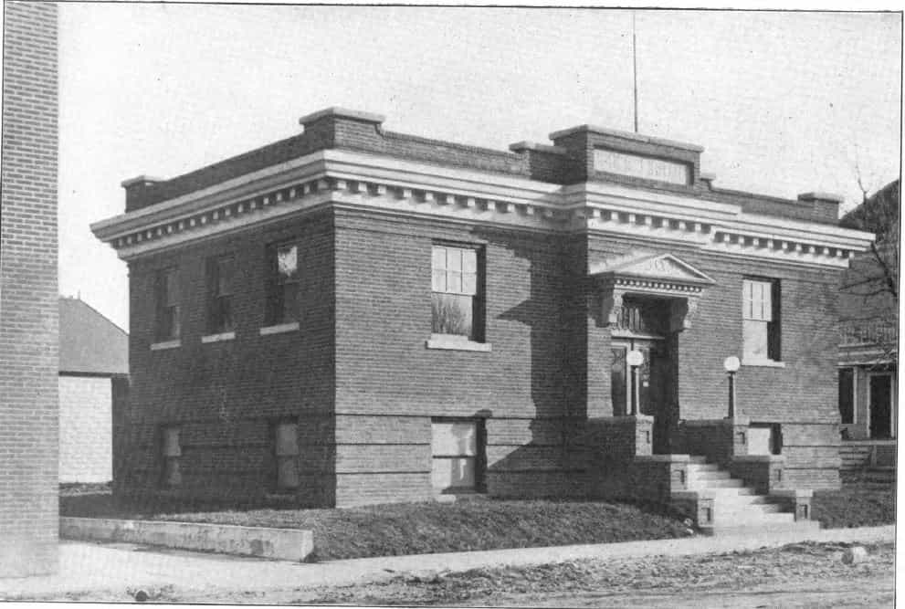 Black and white image showing the front and side exterior of the Grundy Center Public Library. Taken from the 6th Report of the Iowa Library Commission, coverage 1910-1912. (Published in 1913), opposite page 8.