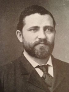 A bust photograph of a younger Bohumil Shimek. He is wearing a suit and tie, and has short dark hair and a short dark beard.