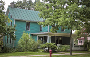 A modern picture of the house that Bohumil Shimek lived in. It is sided a bright turquoise blue and has a large front porch with square columns.