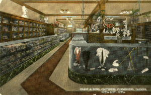 A postcard for Coast & Sons Clothiers Furnishers Tailors store. It is a full color depiction of the store, showing various types of clothes and accessories in glass cases and shelves.