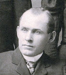 A close up black and white photograph of Samuel Stevenson. He is wearing a suit and tie with short hair and no beard.